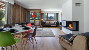 A modern living room with a fireplace, dining area, and a view of the outdoors. - Duplex 2-bed apartment, terrace, near slopes in Megève (Megève)