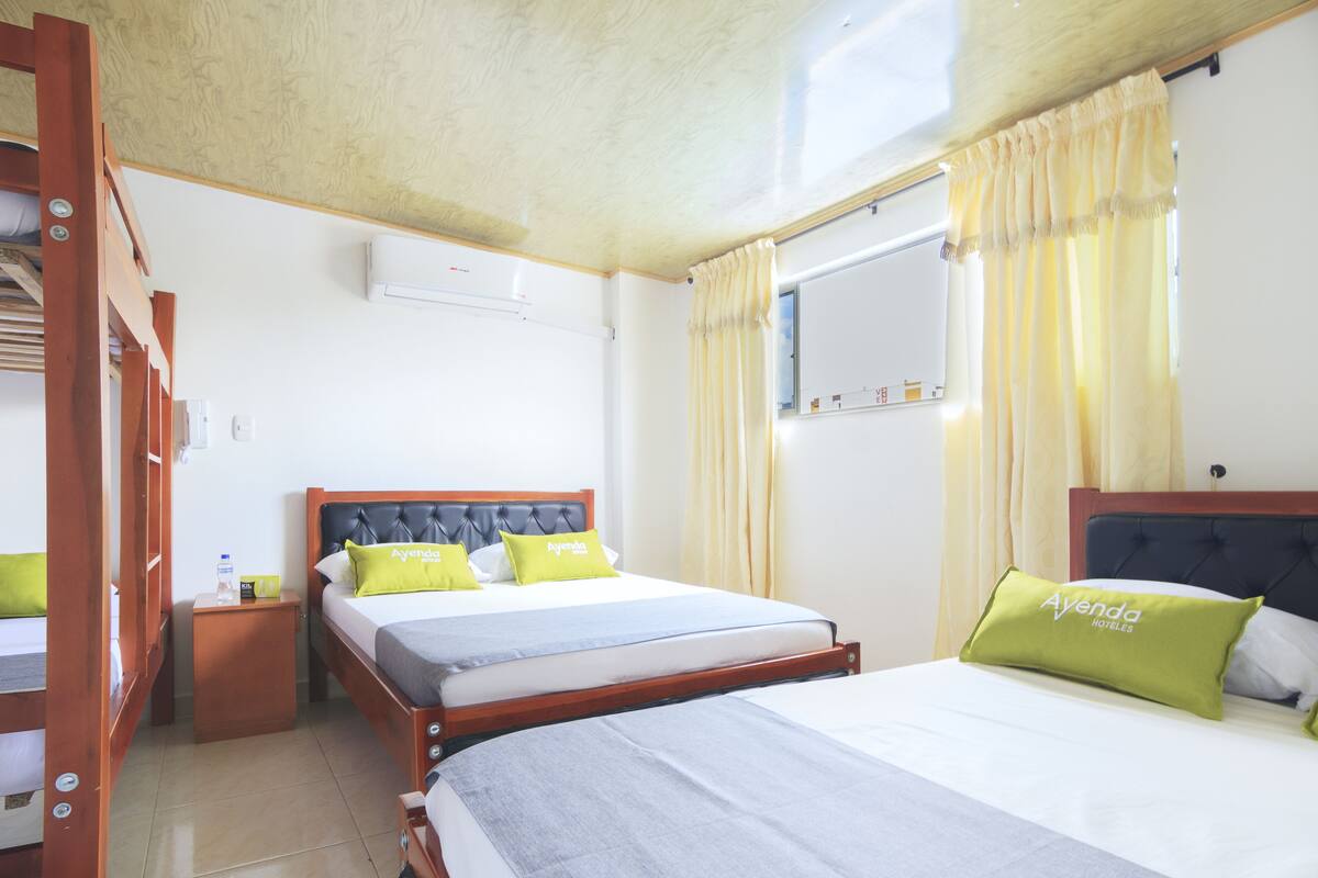 Une chambre d’hôtel avec deux lits, une tête de lit en bois, une table de chevet et une fenêtre avec des rideaux.