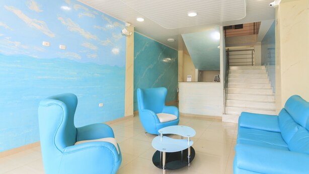 Eine Lobby mit blauen Sitzgelegenheiten, einem Empfangstresen und einer Treppe.