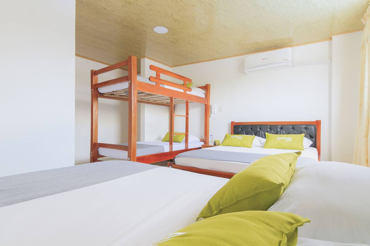 Une chambre avec des lits superposés, un lit simple et une tête de lit portant une plaque avec un nom.