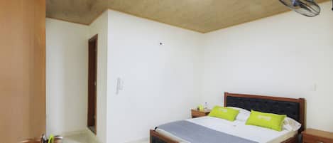 A bedroom with a wooden bed, a nightstand, a bedside table, a ceiling fan, and a door.