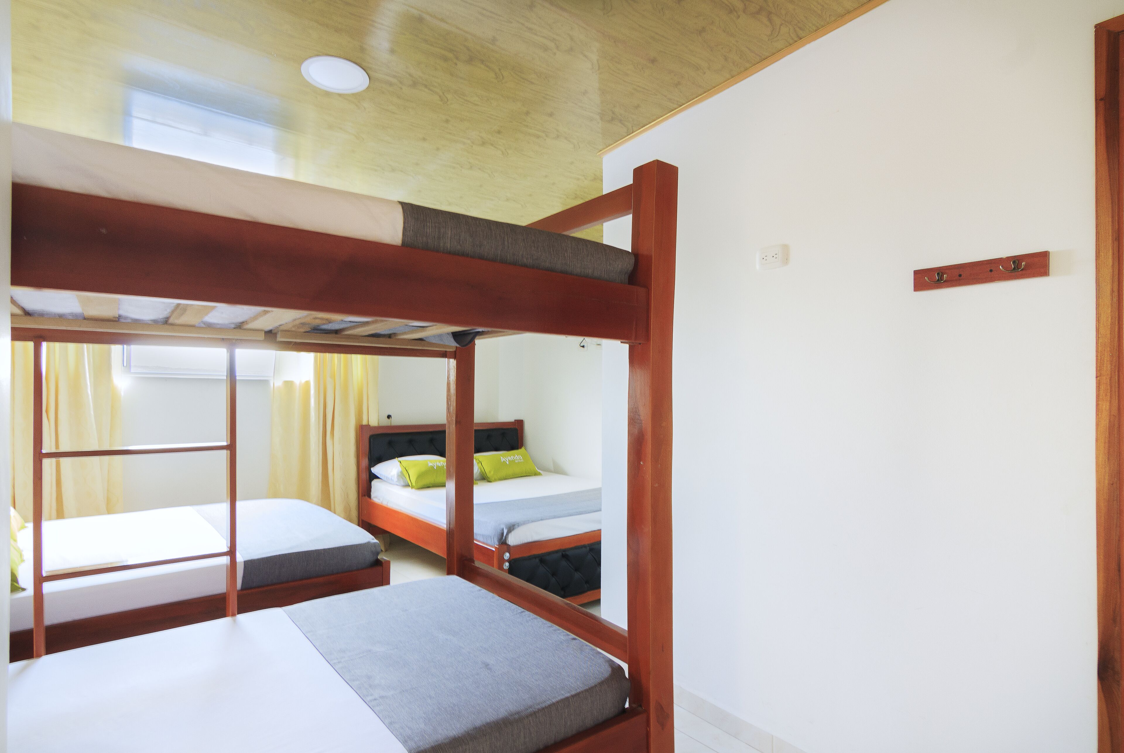 Un dormitorio con literas, techo de madera y ventana con cortinas.