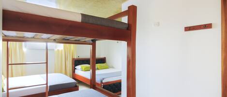 Un dormitorio con literas, techo de madera y ventana con cortinas.