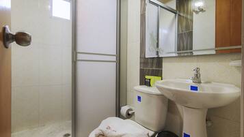 Un baño con inodoro, lavamanos y zona de ducha.