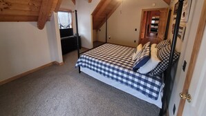A bedroom with a checkered bedspread, a ceiling fan, and wooden beams. - Nolin Lake Log Cabin ~ Beautiful Water Views ~ Great Family Getaway!  (Mammoth Cave)