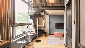 Un intérieur moderne avec un parquet en bois disposé en chevrons, un escalier, un bureau avec une lampe et un téléviseur.