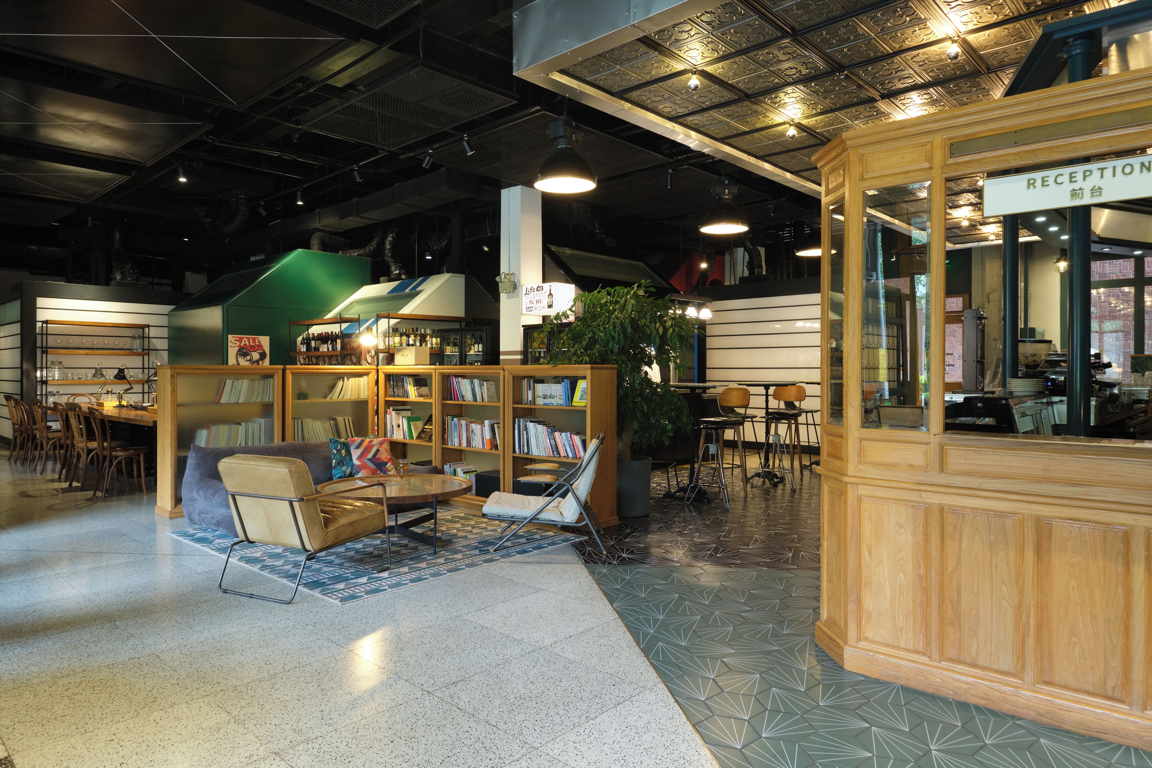 A reception area with a wooden reception desk, a seating area with a sofa and chairs, and a bookshelf filled with books.