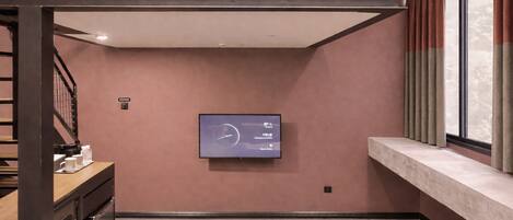 A modern interior with a flat-screen TV mounted on the wall, a wooden bench, and a sofa.