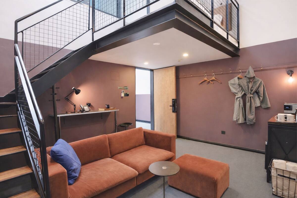Een modern interieur met een trap, een bank, een klein rond tafeltje en een badjas aan de muur.