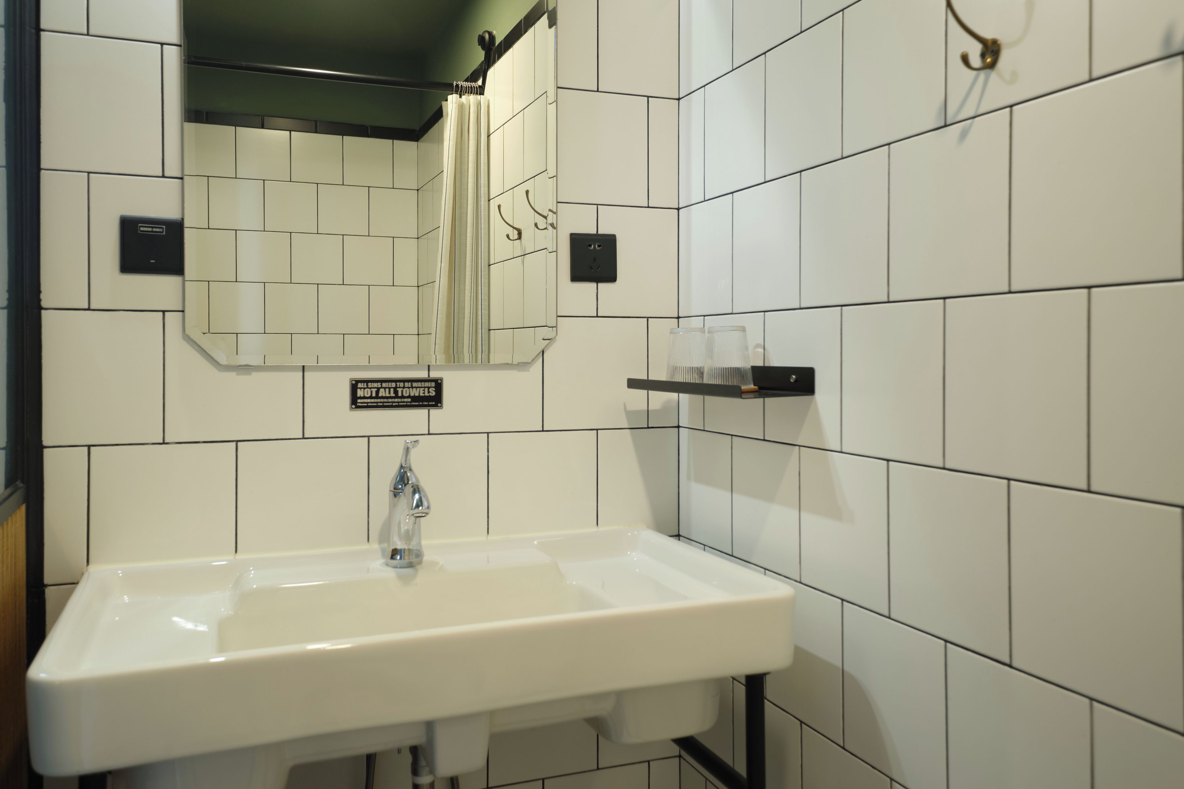 A bathroom with a white sink, a mirror, and a sign indicating the need to wash towels.