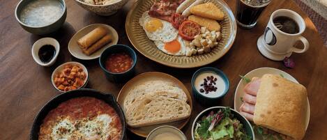 A variety of breakfast items including eggs, toast, and a salad on a wooden table.
