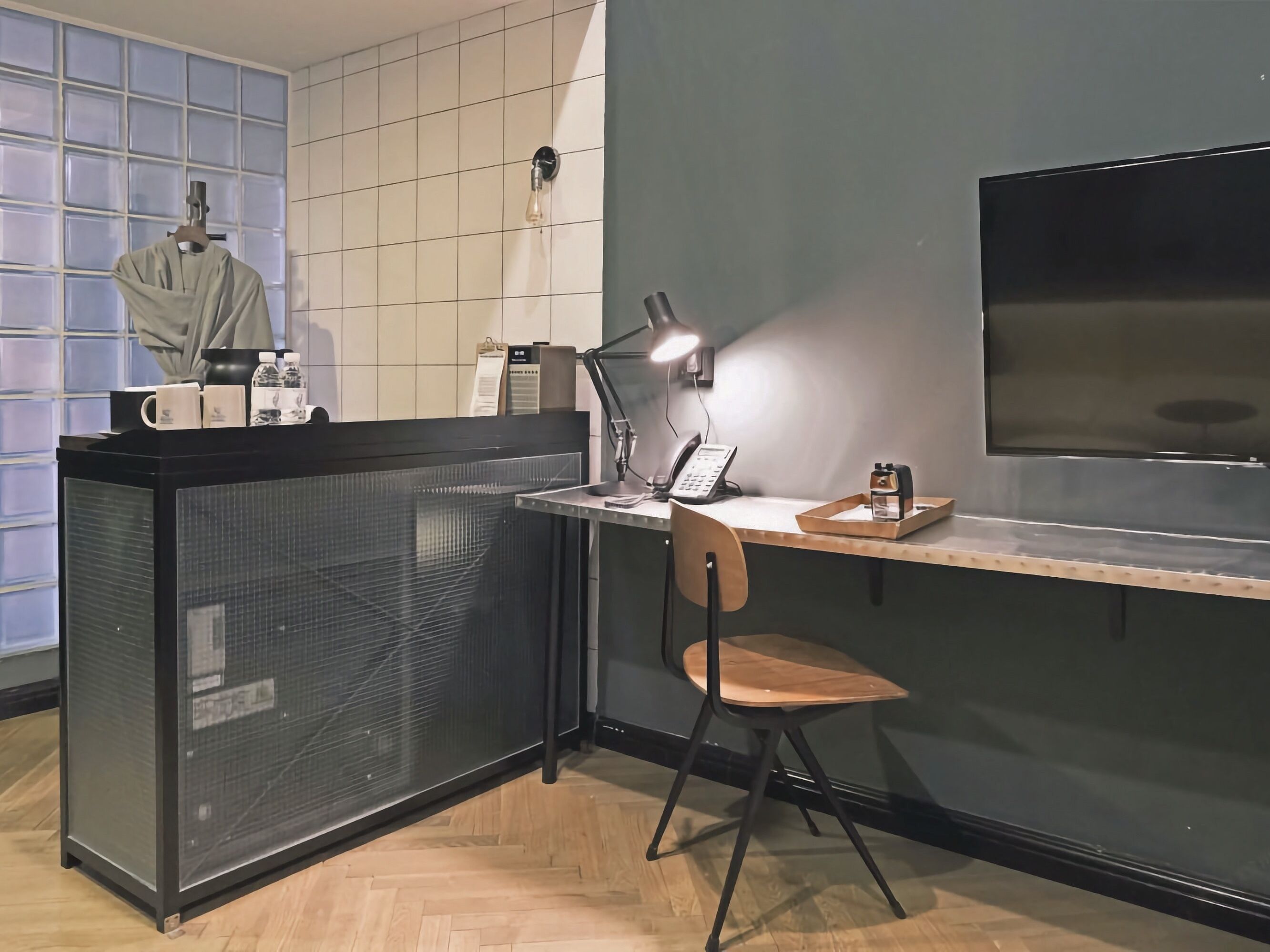 Pieni, käytännöllinen keittiö, jossa on puinen työtaso, tuoli, lamppuvarusteinen työpöytä, kahvinkeitin ja televisio.