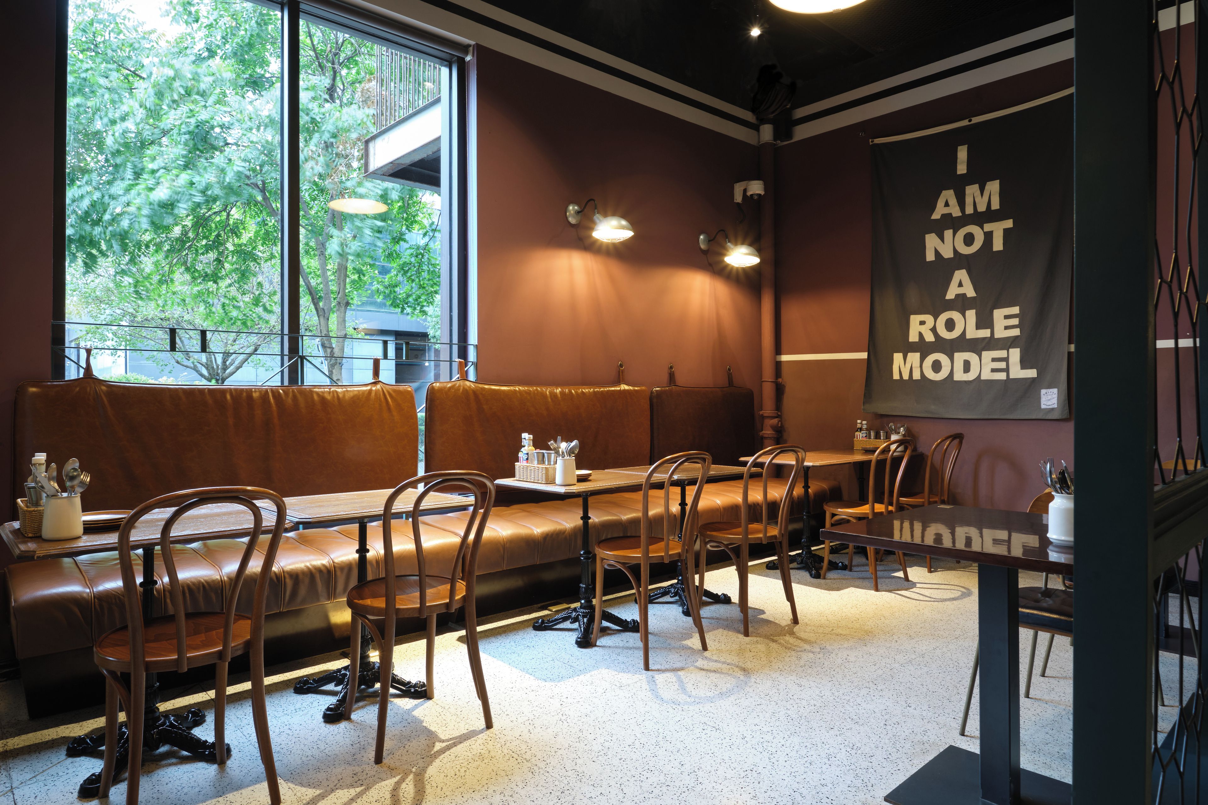 A restaurant interior with a long bench seating area, tables, and chairs.
