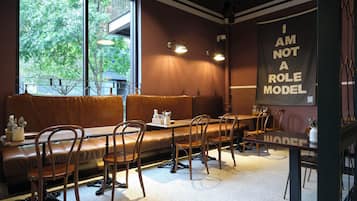 A restaurant interior with a long bench seating area, tables, and chairs.