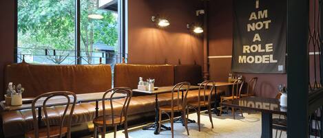 A restaurant interior with a long bench seating area, tables, and chairs.