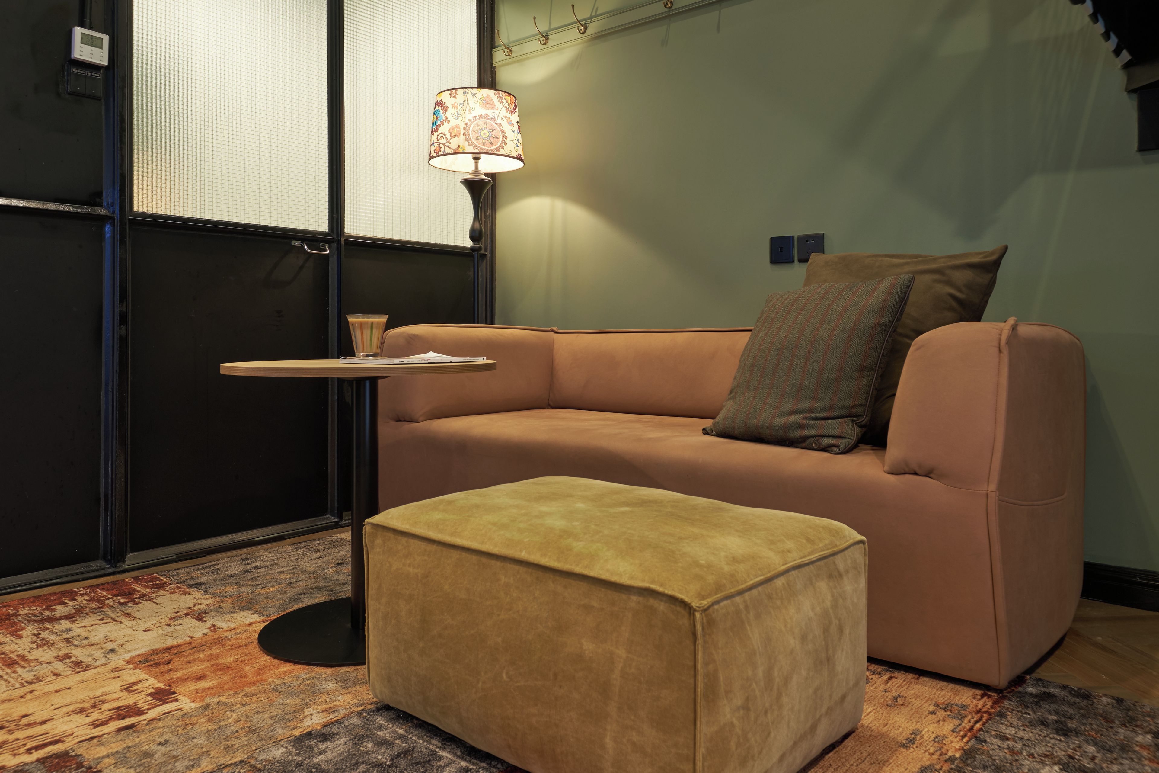 A room with a sofa, a small table, a lamp, and a patterned rug.