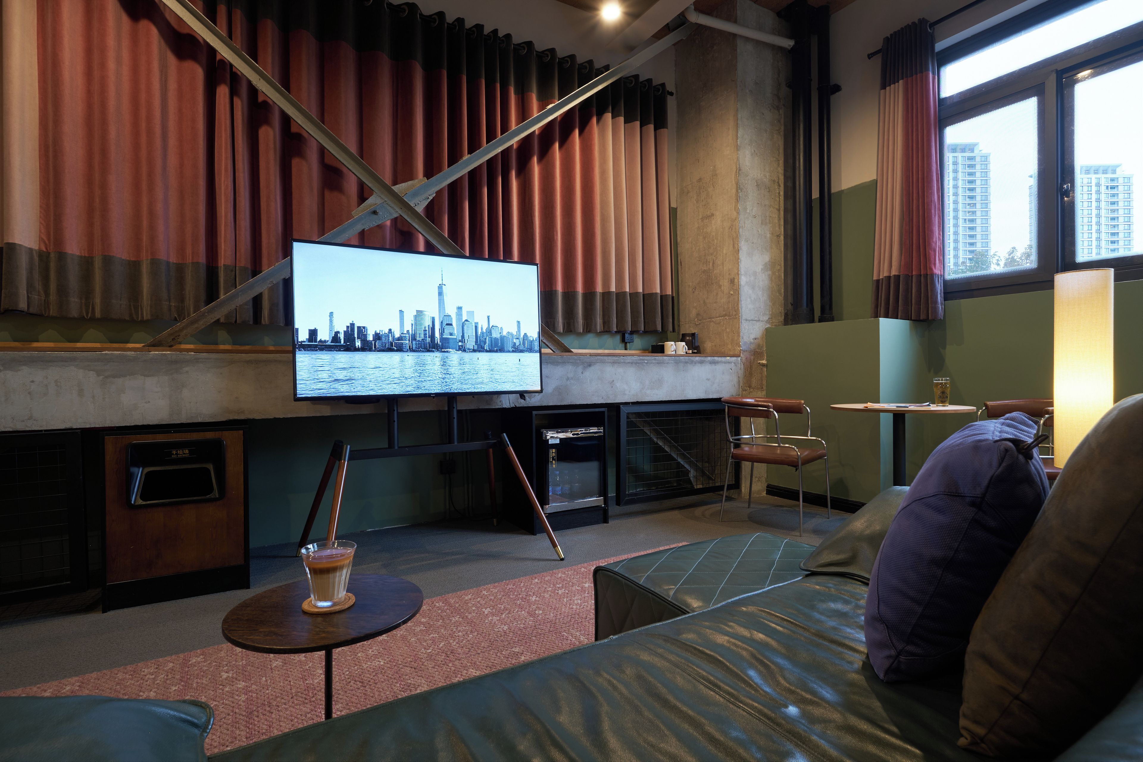 Un salon moderne doté d’un grand téléviseur à écran plat fixé au mur, d’un canapé, d’une table basse et d’une fenêtre avec des rideaux.