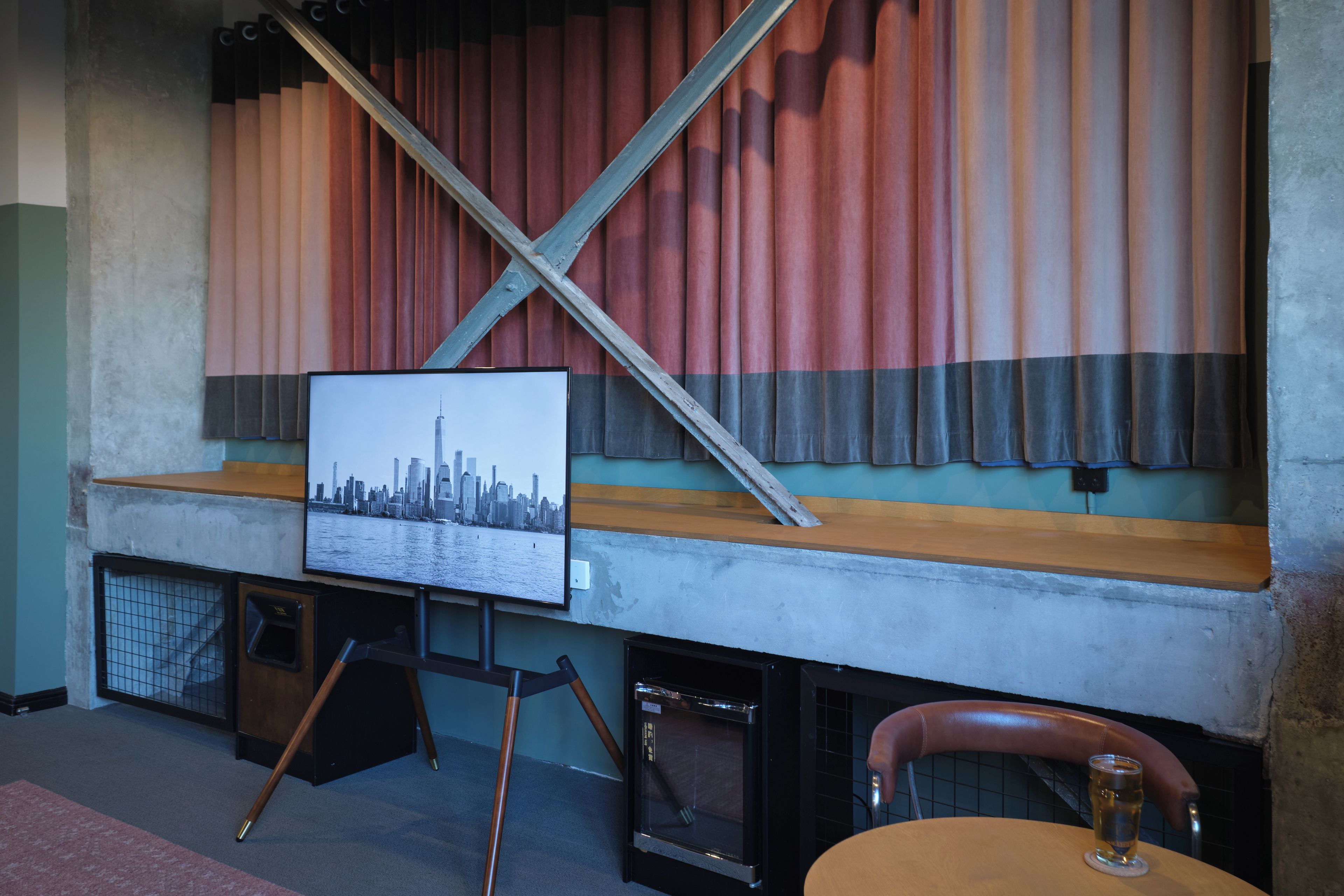 A room with a television mounted on a wall, a wooden bench, and a chair.