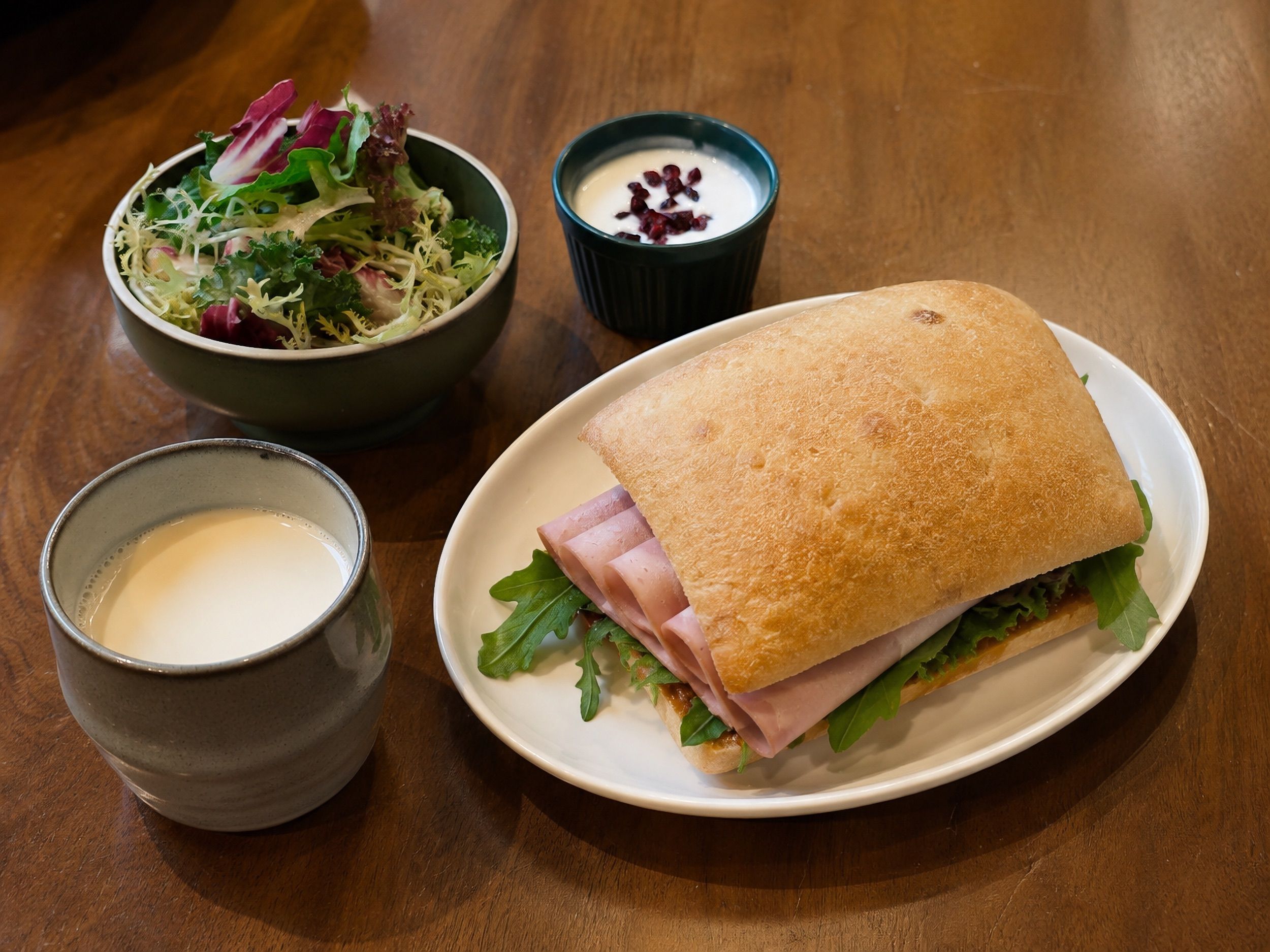 Un repas composé d’un sandwich, d’une salade et d’une tasse d’une boisson crémeuse.