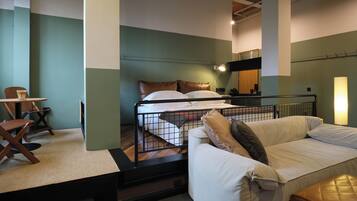 A hotel room with a bed, a sofa, a chair, and a small table.