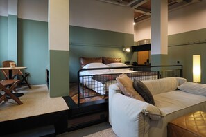 Une chambre d’hôtel avec un lit, un canapé, une chaise et une petite table.