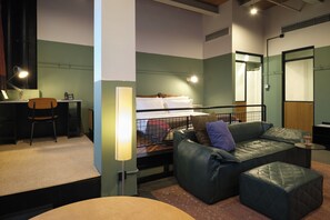 Une pièce comprenant un lit, un bureau, une chaise, un canapé et une petite table.
