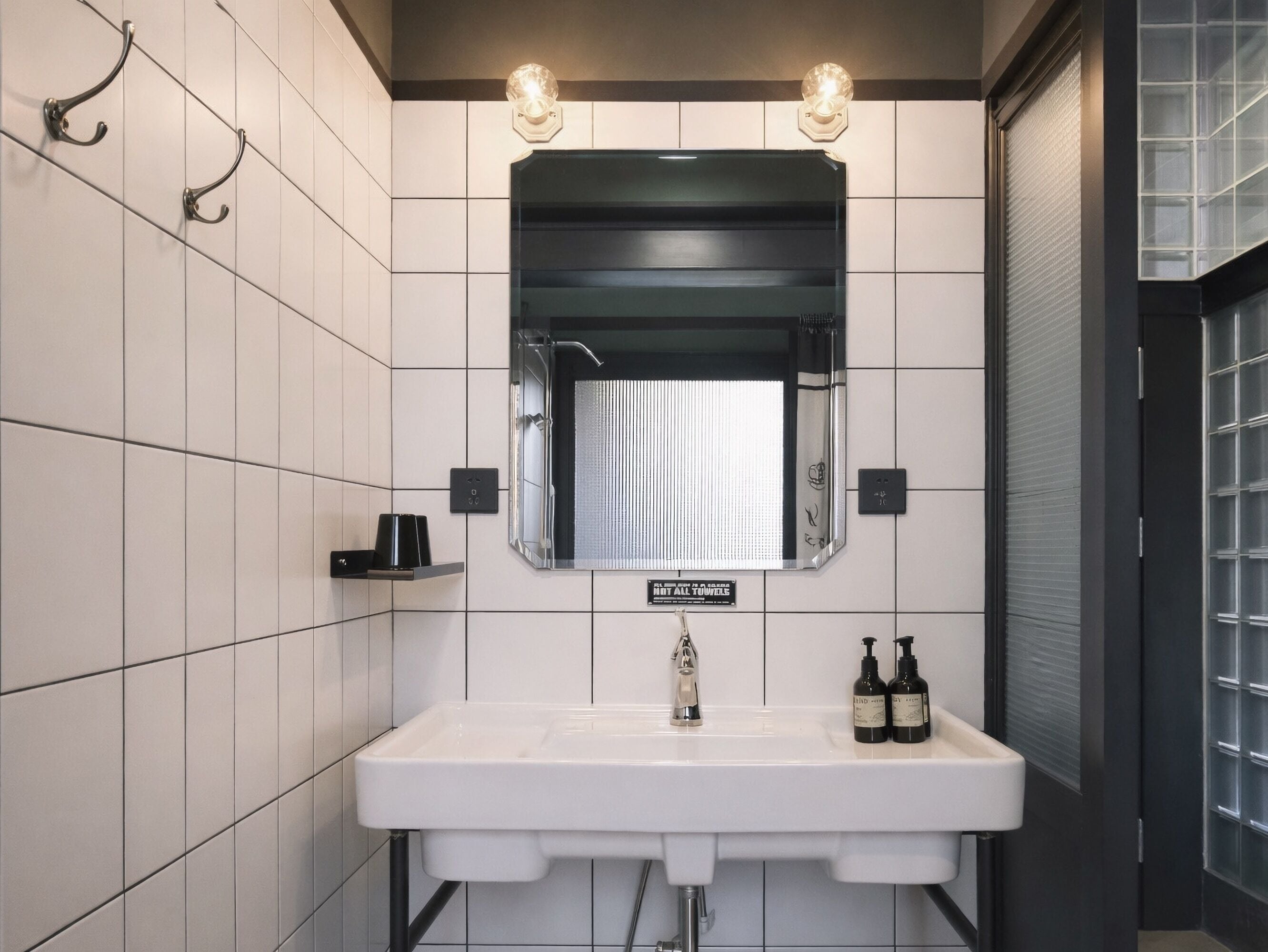 A modern bathroom with a white sink, a mirror, and two wall-mounted lights.