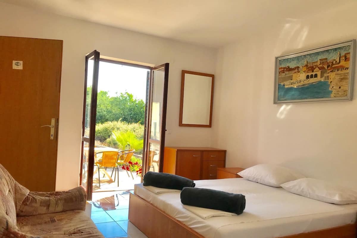 Ein Schlafzimmer mit Bett, Stuhl, Schreibtisch und Blick ins Freie.