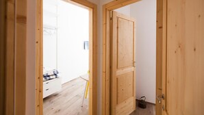 Una puerta de madera que da a una habitación con pared blanca y suelo de madera.
