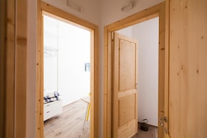 Una puerta de madera que da a una habitación con pared blanca y suelo de madera.