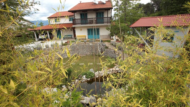 A two-story house with a red-tiled roof, a balcony, and a stone structure in the yard. - Villa Salamander (Komen)