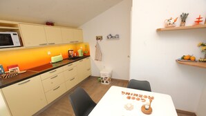 A compact kitchen with a microwave, toaster, and various appliances on the counter. There is a dining table with chairs and a sign that reads "Good Morning". - Villa Salamander (Komen)