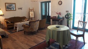 A cozy living room with a wooden floor, a chandelier, a sofa, a coffee table, and a dining table with chairs. - Villa Salamander (Komen)