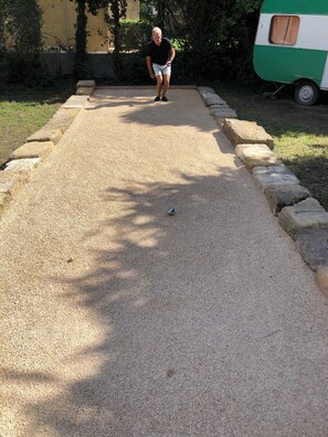 Alguém jogando um jogo de gramado, um veículo verde e branco, e uma área pavimentada com borda de pedra.