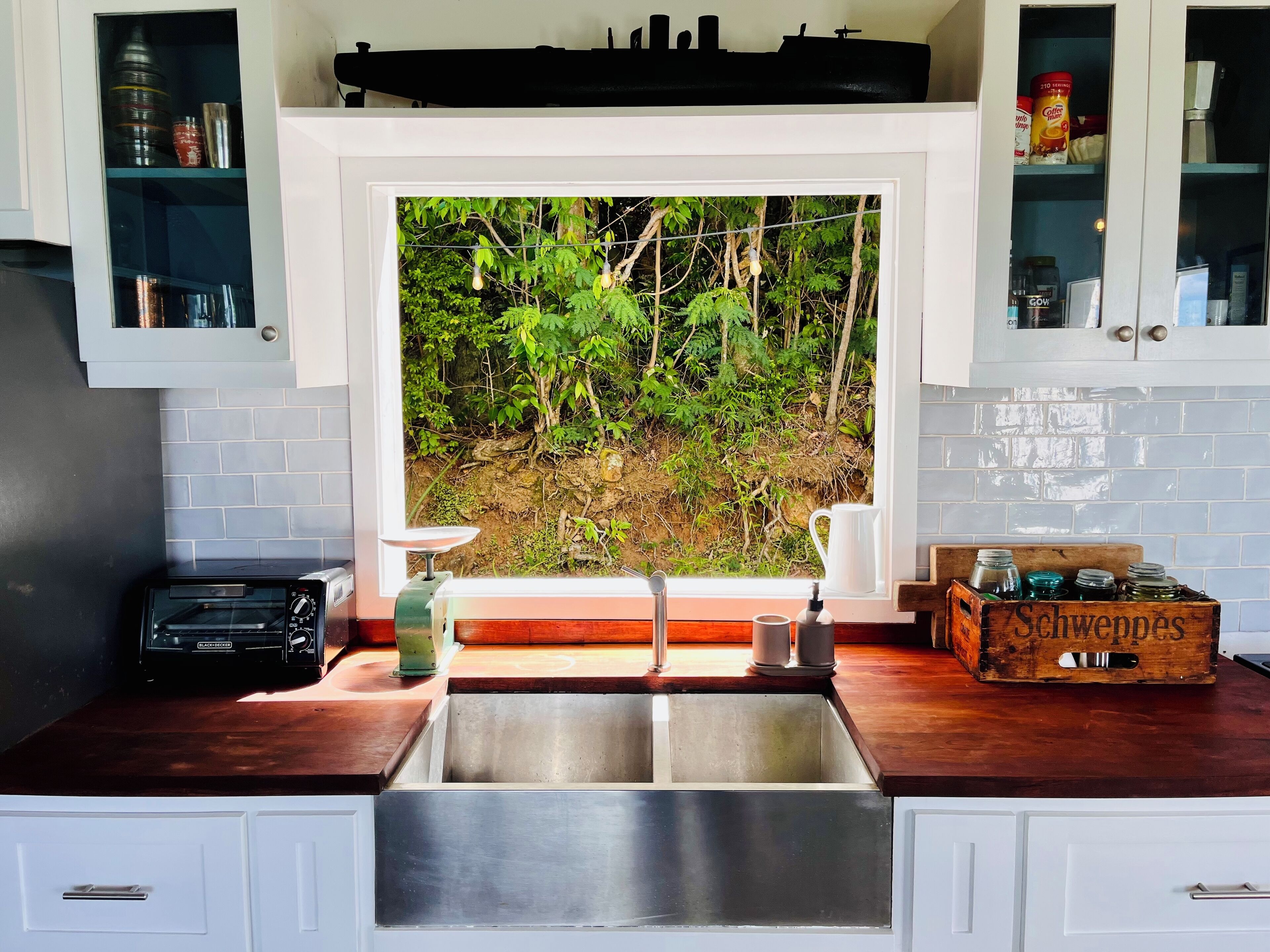 Une cuisine dotée d’une grande fenêtre, d’un four encastré et d’un plan de travail en bois.