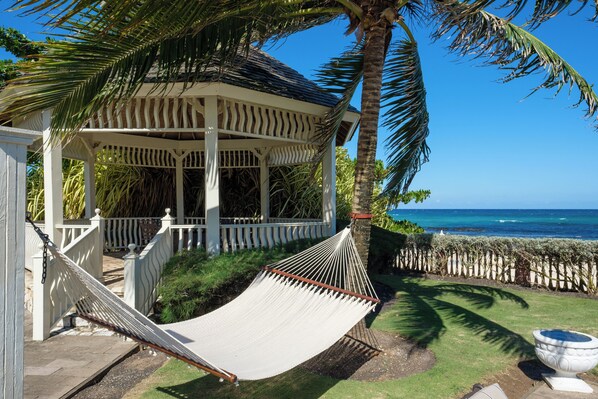A gazebo with a hammock, a palm tree, and a view of the ocean. - Villa Paradiso, Mammee Bay, Ocho Rios, Jamaica (Steer Town)