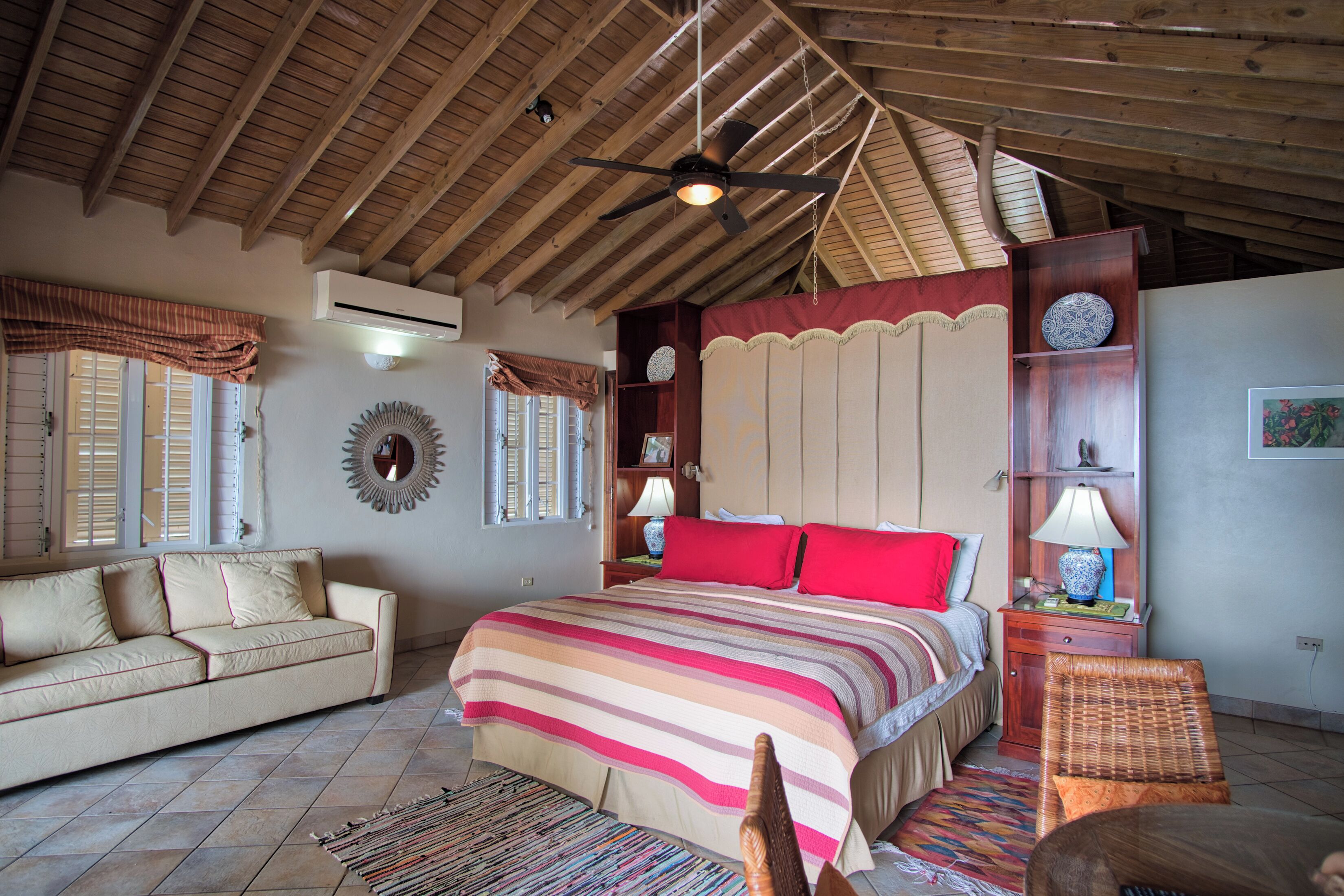 A cozy bedroom with a large bed, a sofa, and a ceiling fan.