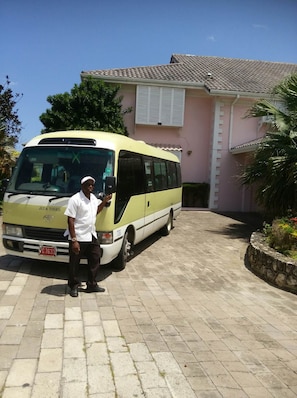 A yellow bus parked in front of a building with a tiled roof and white shutters. - Villa Paradiso, Mammee Bay, Ocho Rios, Jamaica (Steer Town)