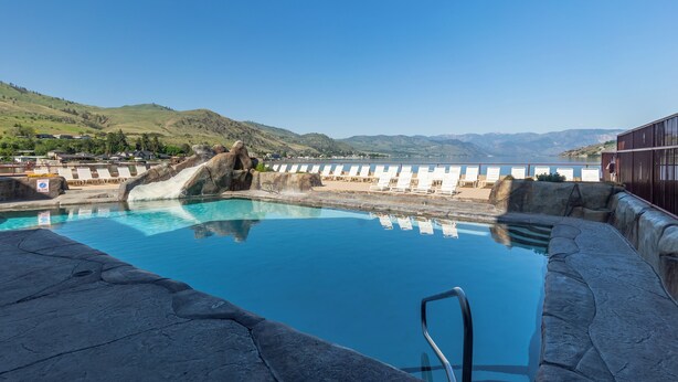 A swimming pool with a clear view of the surrounding landscape, including hills and a body of water.