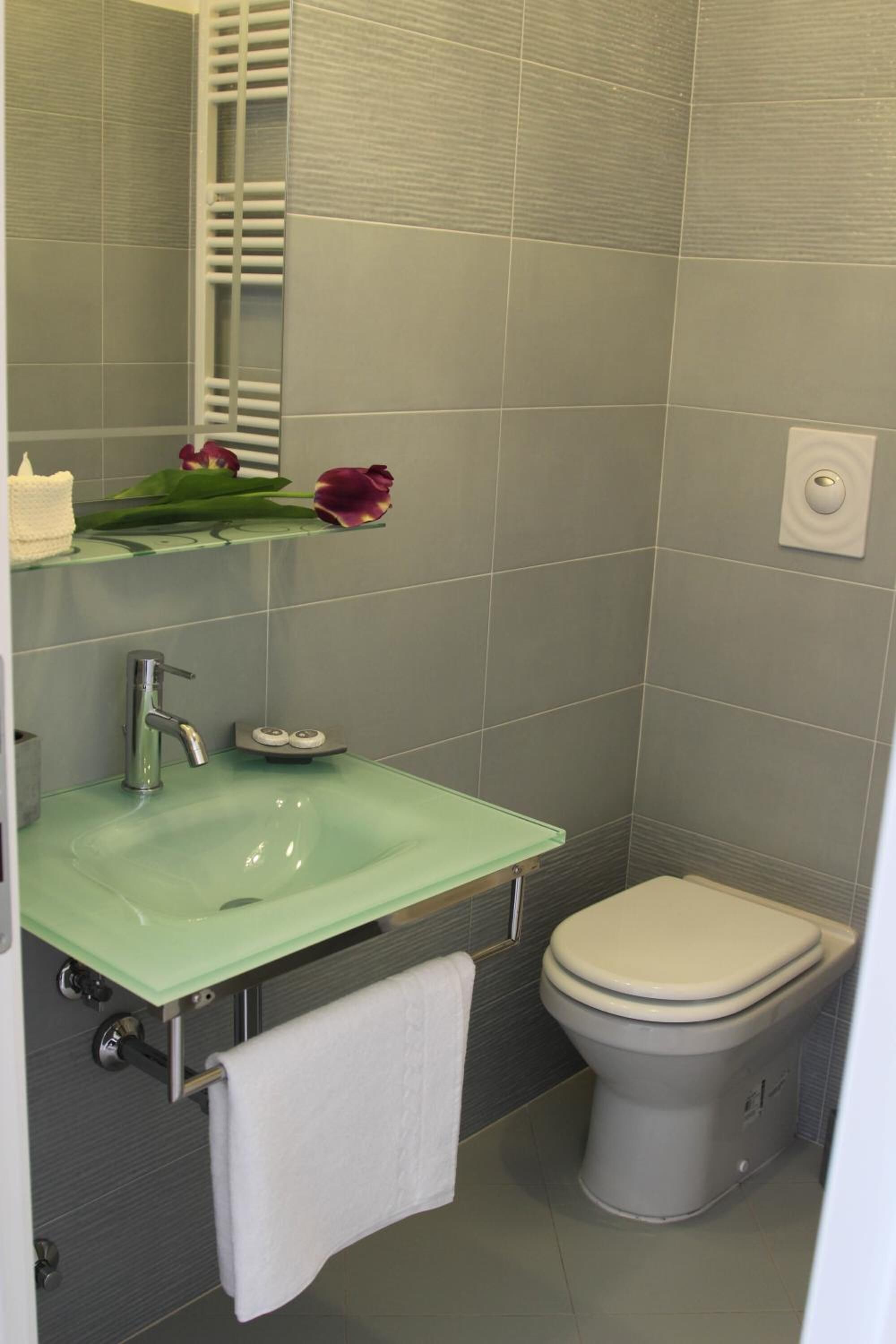 Casa de banho com lavatório verde, sanita branca e suporte para toalhas.