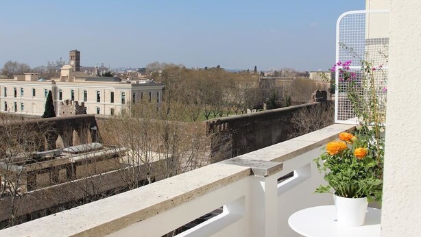Un balcón con vista a un paisaje urbano, que incluye edificios y un puente.