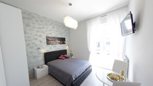 Un dormitorio moderno con cama, mesita de noche y una pequeña mesa con comida y bebidas.