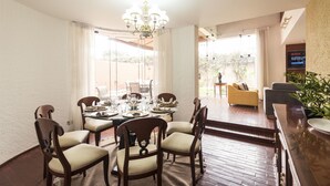 A dining area with a table set for six, surrounded by wooden chairs with cushioned seats. A chandelier hangs from the ceiling, and a television is mounted on the wall. - Lima Fabulous  House 5br sleep8 Next Mall (Lima)