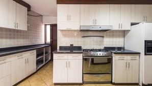 A kitchen with light-colored cabinets, a gas stove, an oven, and a refrigerator. - Lima Fabulous  House 5br sleep8 Next Mall (Lima)