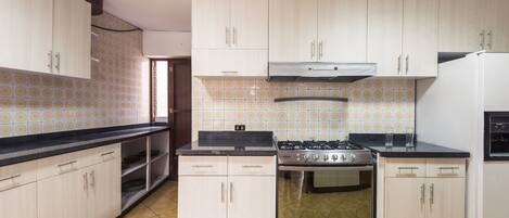 A kitchen with light-colored cabinets, a gas stove, an oven, and a refrigerator.