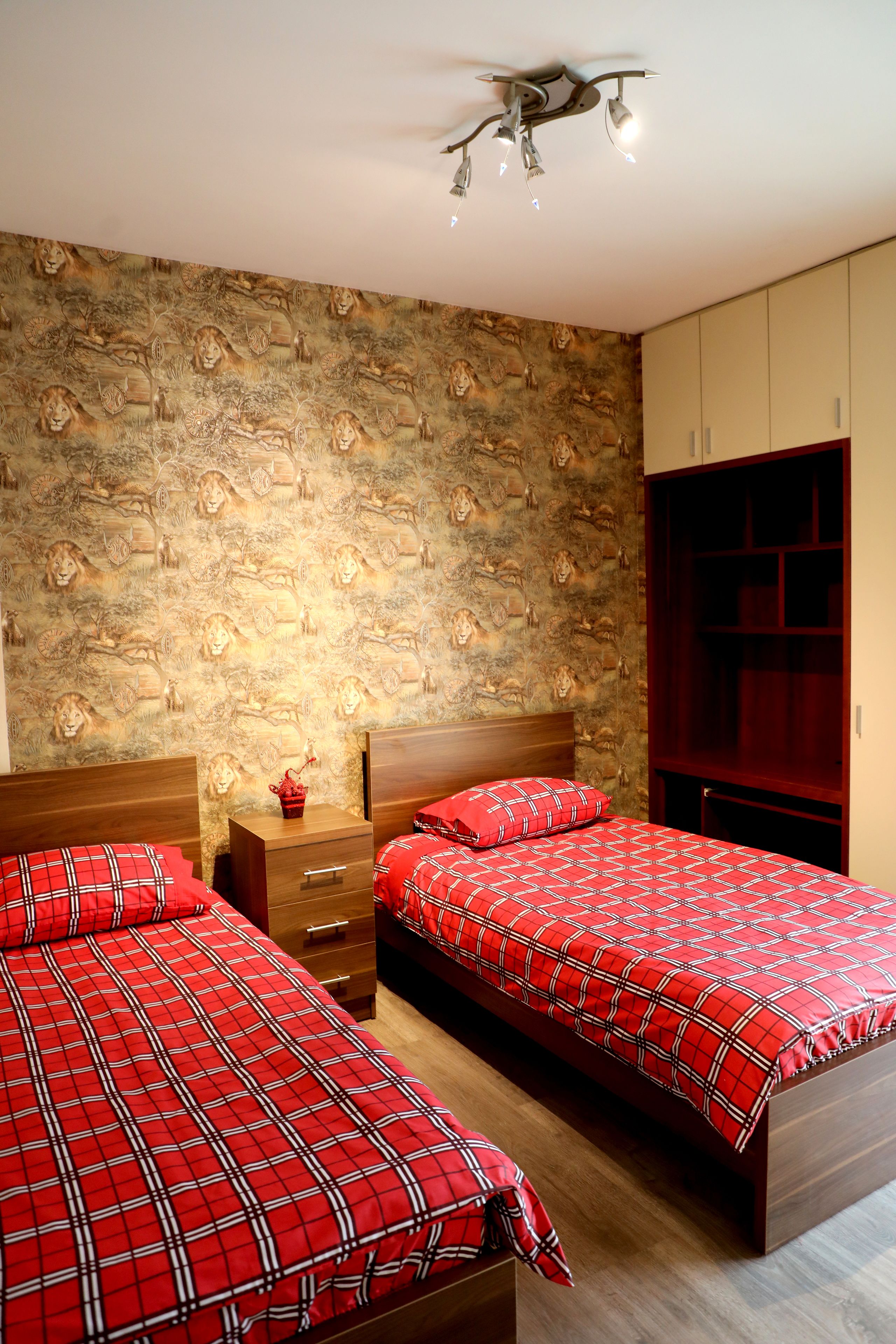 Un dormitorio con dos camas, cabecero de madera, mesita de noche y armario.