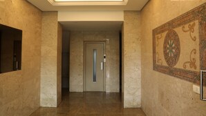 A hallway with a marble floor, a door with a vertical handle, and a patterned wall. - Vino Apartment (Zalqa)