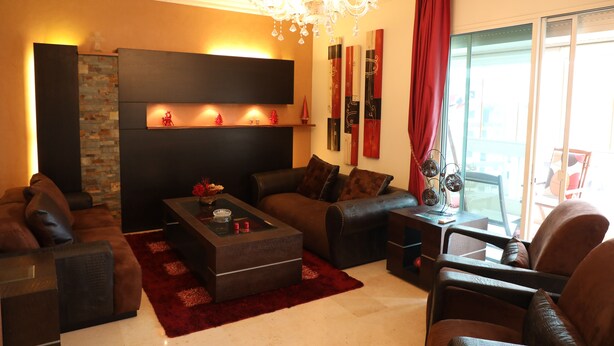 A modern living room with a fireplace, leather sofas, a coffee table, and a chandelier. - Vino Apartment (Zalqa)