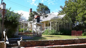 A traditional house with a porch, a chimney, and a garden with a stone wall and steps. - The Baines House Inn (Salado)