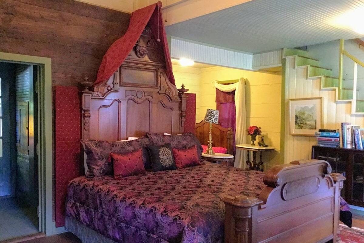 A bedroom with a four-poster bed, a wooden headboard, and a red canopy.